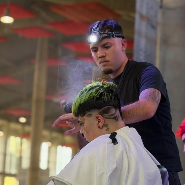 Diseño a navaja a un cliente con el pelo verde durante una competición